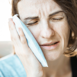 Woman using a cold compress for toothache at night relief