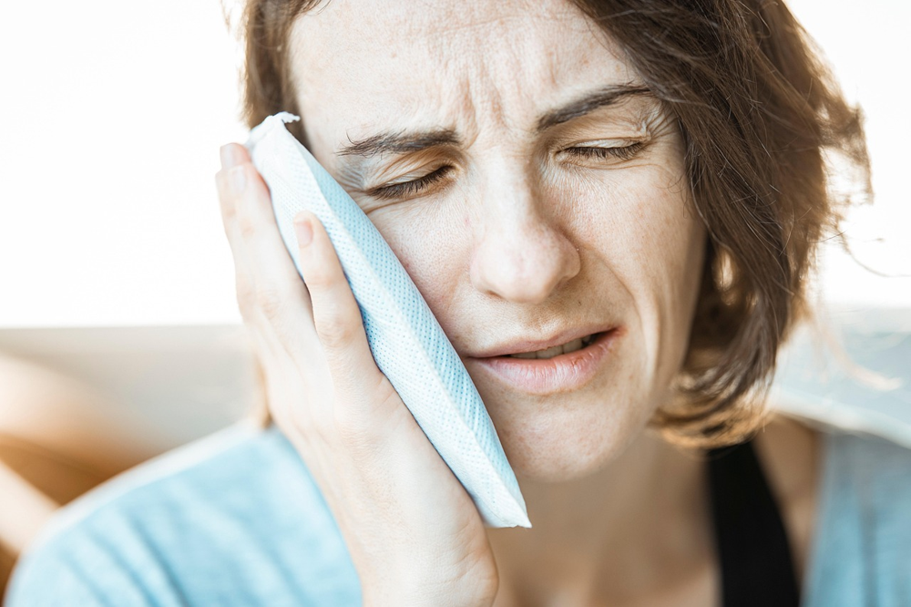 Woman using a cold compress for toothache at night relief