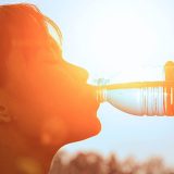 Woman sipping a cold drink with a painful expression under the sun.