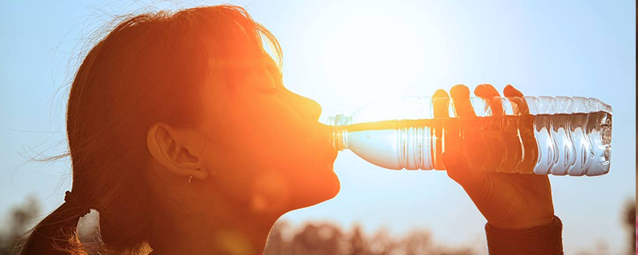Woman sipping a cold drink with a painful expression under the sun.