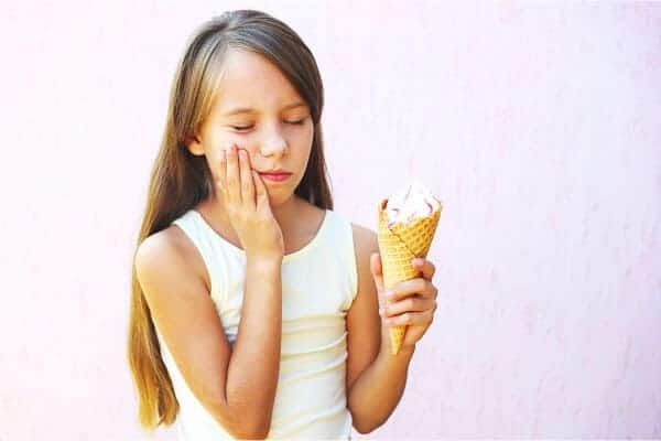 Child experiencing tooth sensitivity from cold ice cream